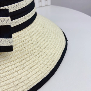 Detail of cream woven sun hat featuring black grosgrain ribbon and textured wave patterns
