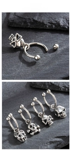 Macro detail of gothic titanium steel horseshoe earrings with skull charms on stone background