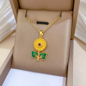 Close-up of golden sunflower pendant with yellow enamel petals on white silk background