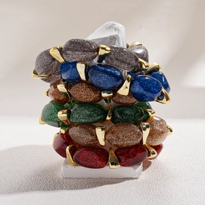 Colorful acrylic bead bracelets with gold accents on white stone display stand