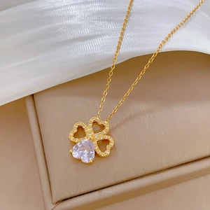Elegant gold titanium steel clover necklace with heart-shaped zircon on white silk background