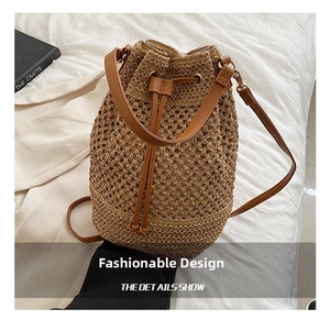 Detail view of woven straw bucket bag with dark brown leather drawstring and slim strap