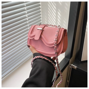 Close-up of pink mini saddle bag with silver chain strap and metallic buckle closure