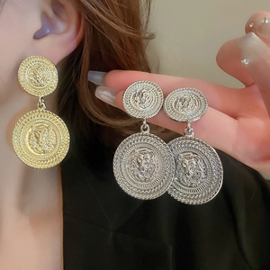 Detailed view of oversized vintage lion head embossed gold and silver metal earrings