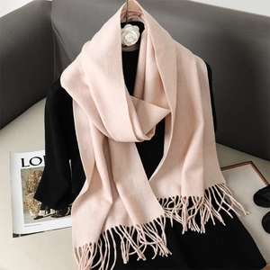 Dettaglio di una morbida sciarpa rosa effetto cashmere con nappe su abbigliamento nero
