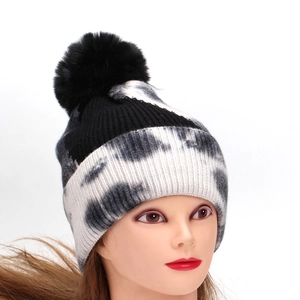 Winter tie-dye knit beanie featuring a black faux fur pompom and thick cuffed edge