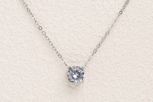 Close-up of classic 18K silver-plated stainless steel necklace with four-prong zircon pendant