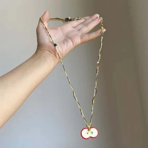 Detail of bohemian red resin apple pendant with colorful twisted woven fiber rope