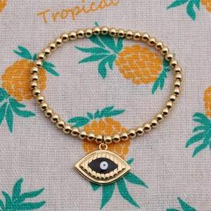 Detail of gold beaded stretch bracelet with black and white enamel evil eye charm