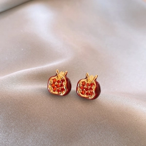 Macro view of red garnet stud earrings with gold edges on silver silk background
