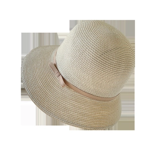 Close-up of spiral hand-woven texture and elegant bow on a beige straw sun hat