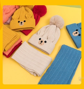 Detailed flat lay of colorful knit beanies and scarves with bear ears and pom-poms