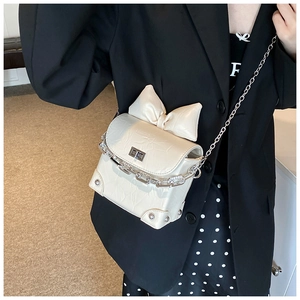 Detail of cream crossbody bag featuring bow decoration and stylish pleated texture