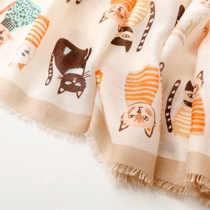 Close-up of cute cat print on beige scarf fabric with soft texture and tassel details
