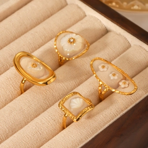 Four gold stainless steel open rings with shell flower inlays on velvet jewelry box lining