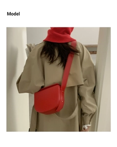 Chic red faux leather saddle bag worn over a beige trench coat with matching red beret