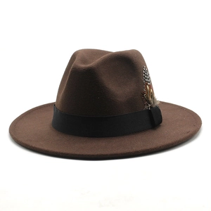 Detail of a brown wool fedora hat featuring a black ribbon band and elegant feather accent