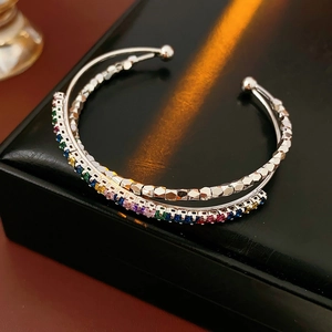 Detail of cross-layered open bangle with rainbow zircon stones on black leather