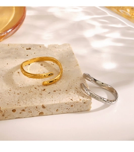 Detail of gold and silver hammered stainless steel open rings on a stone surface