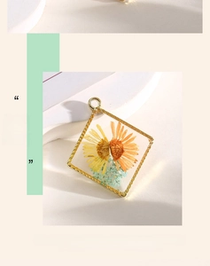 Detail of square gold alloy pendant with real dried yellow daisies and blue flowers