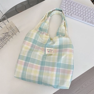Macro detail of pastel plaid tote bag with woven texture and a stitched logo label