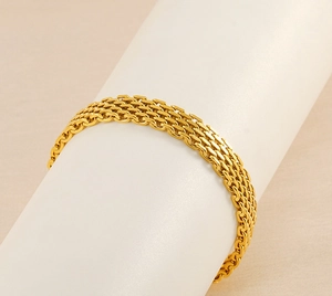 Macro shot of gold stainless steel woven mesh bracelet on a white cylinder display
