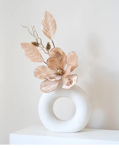 Detail of white ceramic circular vase with champagne faux magnolia and golden branches