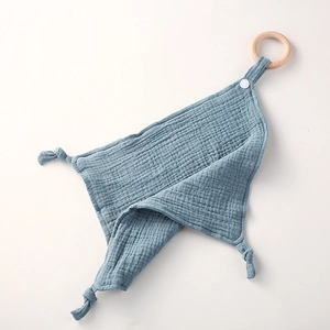 Detailed view of dusty blue cotton muslin baby comforter with natural wooden teething ring
