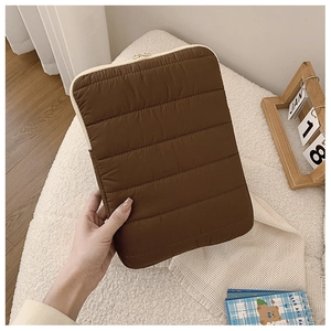 Detail of dark brown quilted laptop sleeve showing soft texture and cream zipper closure