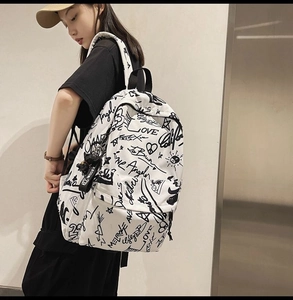 Close-up of street graffiti canvas backpack with black letter prints and XBOOM charm