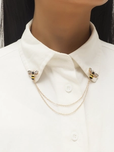Detail of bee collar pins with gold double chain and rhinestones on a white shirt