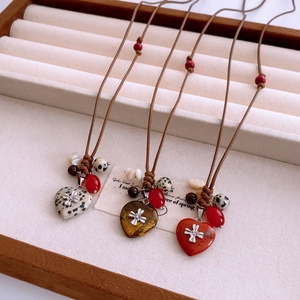 Détail de pendentifs cœur en pierre naturelle avec incrustations florales sur cordon
