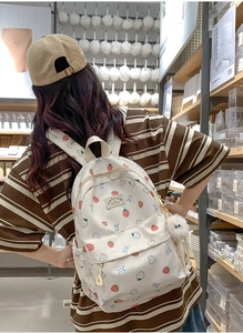 Detail of strawberry print backpack showing rear view and size on person in white color