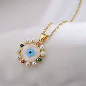 18K gold plated evil eye necklace with pearls and colorful zircons on white fabric