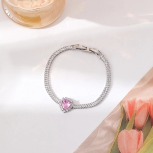 Detail of silver bracelet with heart-shaped pink gemstone and sparkling zircon stones