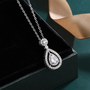 Close-up of teardrop moissanite pendant with halo diamonds on a silver chain