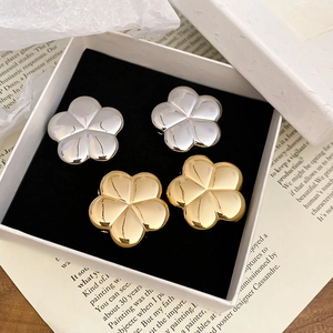 Detailed view of polished gold and silver 3D flower earrings in a premium jewelry box