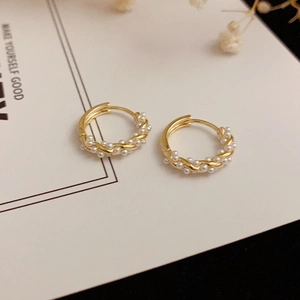 Detailed view of C-shape twisted gold hoop earrings with small pearls on a display card