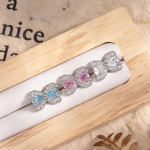 Elegant bow-shaped titanium steel studs with colorful zircons on a wooden display stand