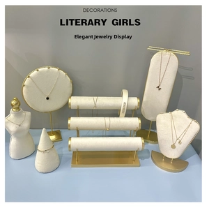 Detailed view of beige velvet jewelry displays with gold metal bases for necklaces and rings