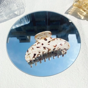 Detail of cream acetate claw clip with tortoise pattern reflected in a mirror