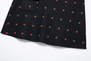 Détail de la broderie fraise et de la poche sur le tissu noir de cet ensemble deux pièces