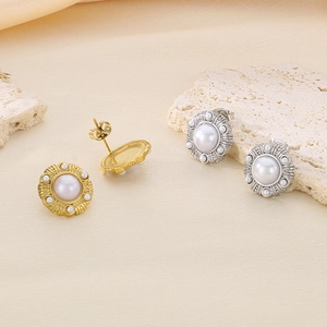 Detailed view of gold and silver pearl stud earrings with textured circular metal borders