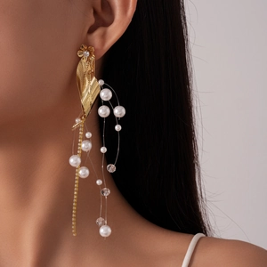 Detail of gold leaf earring with small diamonds and long white pearl tassel on model