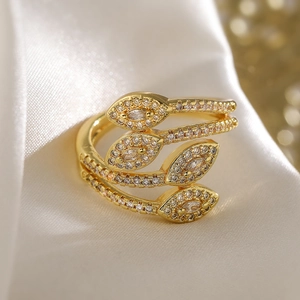 Detail of gold-plated coiled snake ring with sparkling zircons on white silk fabric
