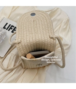 Detail view of woven straw crossbody bag showing interior space for phone and lipstick