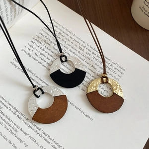 Detail of vintage geometric pendant necklaces with hammered metal and wood textures on a book