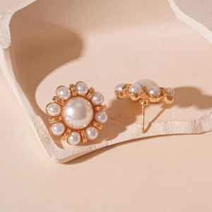 Detailed close-up of French vintage faux pearl flower earrings on a white tray
