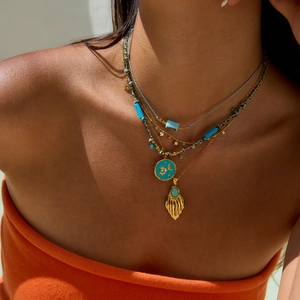 Detail of layered turquoise necklaces with sun moon pendant and gold shell on female neck