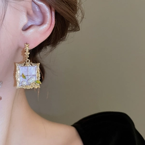 Detail of vintage gold square earrings with lavender enamel and leaf pearl accents